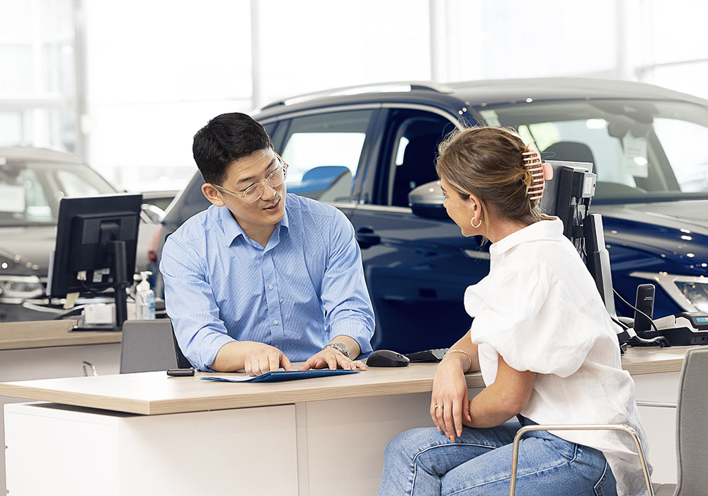A man and woman sit and a Volkswagen desk talking about service plans