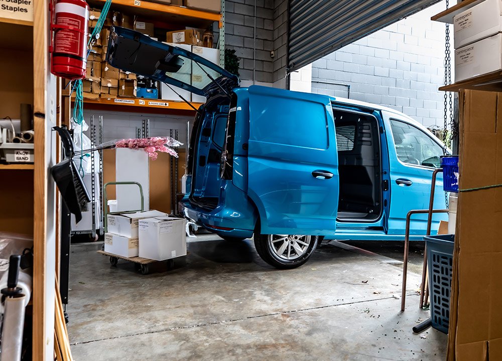 Rear of a blue panel van parked in a commercial space