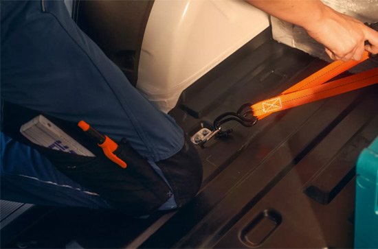 Someone tying fasteners in the rear of a cargo van