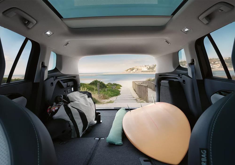 Interior of a Tayron with the rear seats fold and a surf board & luggage being stored