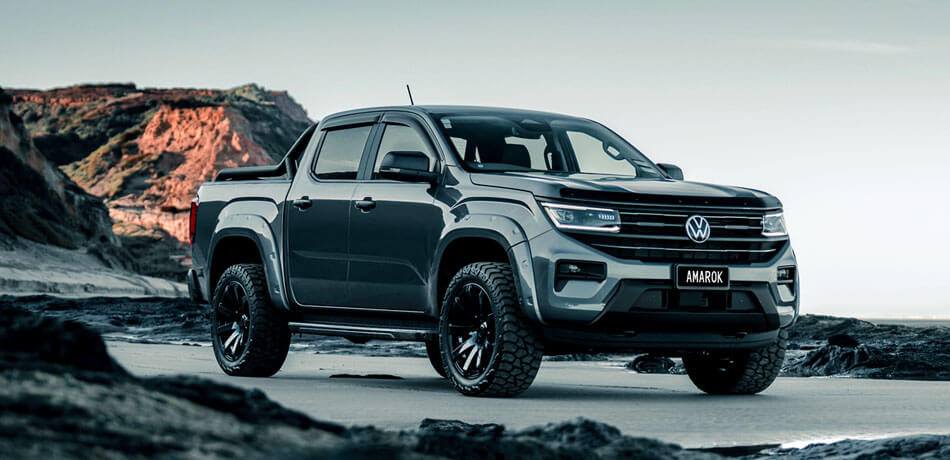 A black Volkswagen Amarok parked on a beach